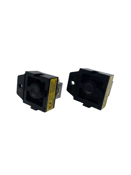 Two black industrial electrical contactors with yellow warning labels, photographed on a light gray background.