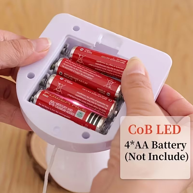 A close-up of a person holding a white cylindrical device with a battery compartment, showing four red CoB LED 1.5V AA batteries inside.