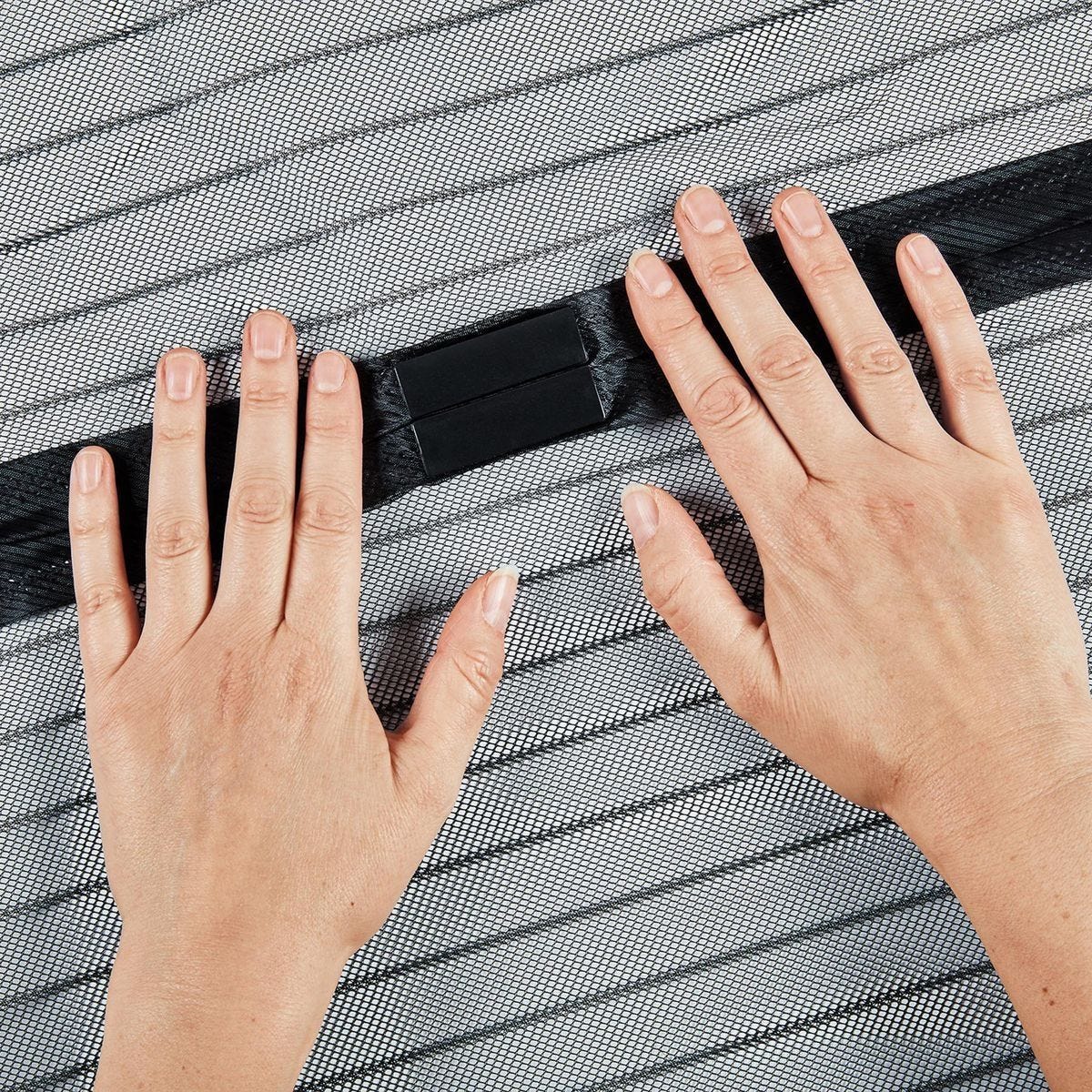 Hands holding a black strip against a textured gray surface