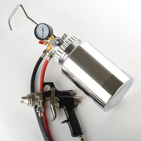 A polished stainless steel spray gun with a black trigger, connected to a red and black hose and a metal gauge, shown on a plain light background.