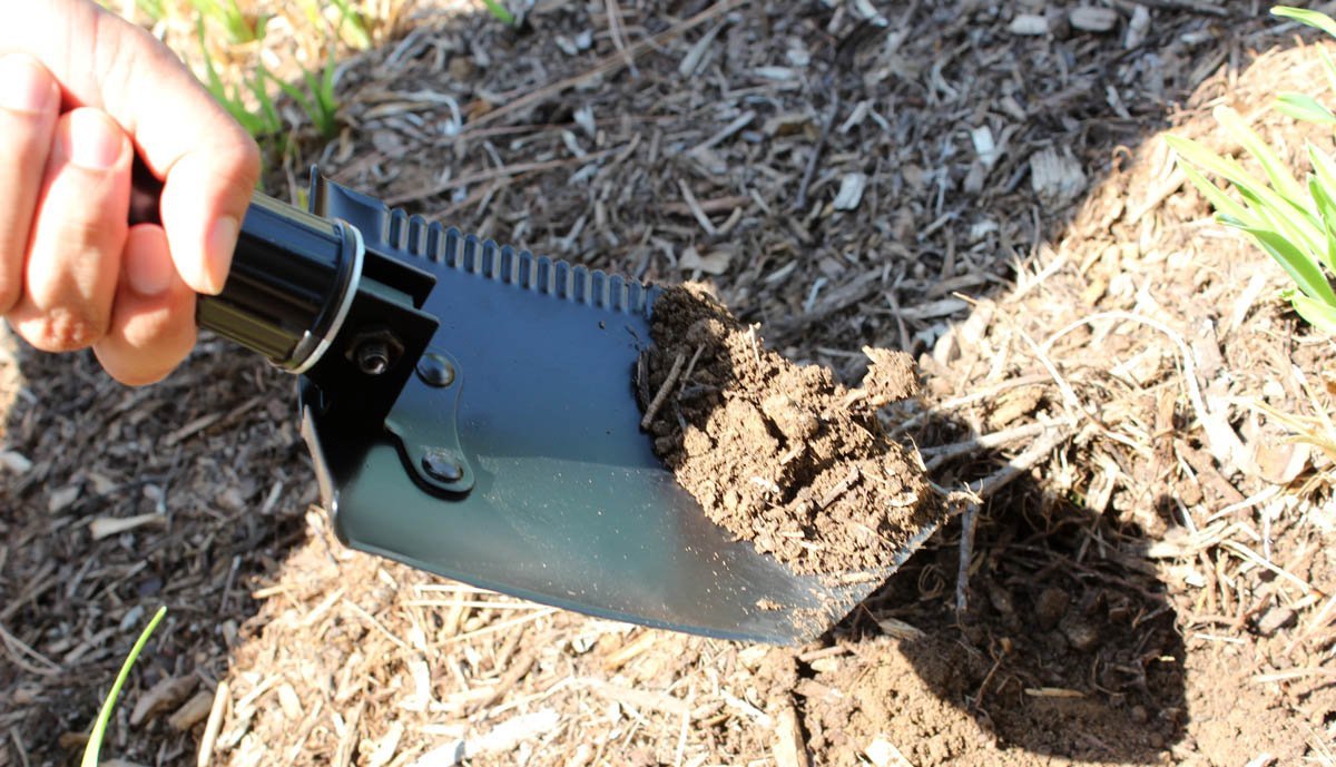Person using a garden tool to dig into the soil