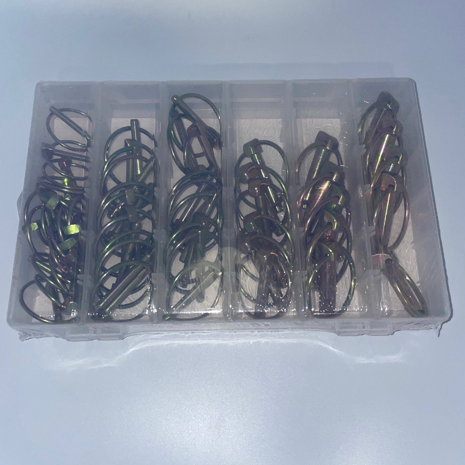 Set of fishing hooks in a clear plastic case on a light gray background