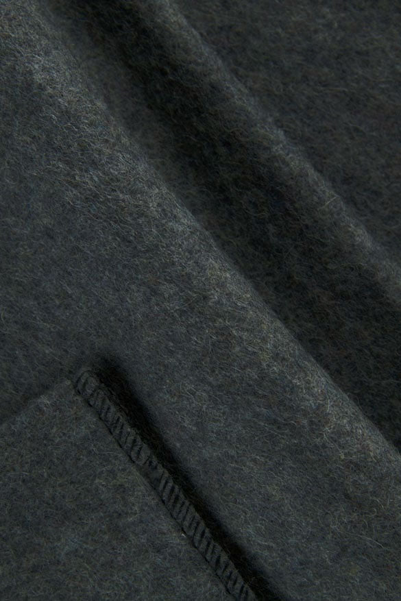 Close-up of dark charcoal gray wool fabric with a visible stitched seam.