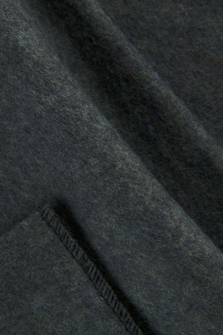 Close-up of dark charcoal gray wool fabric with a visible stitched seam.
