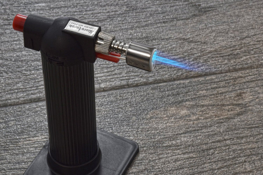 Butane torch with blue flame on a wooden surface