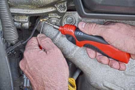 Person using a red and black screwdriver on a mechanical component.