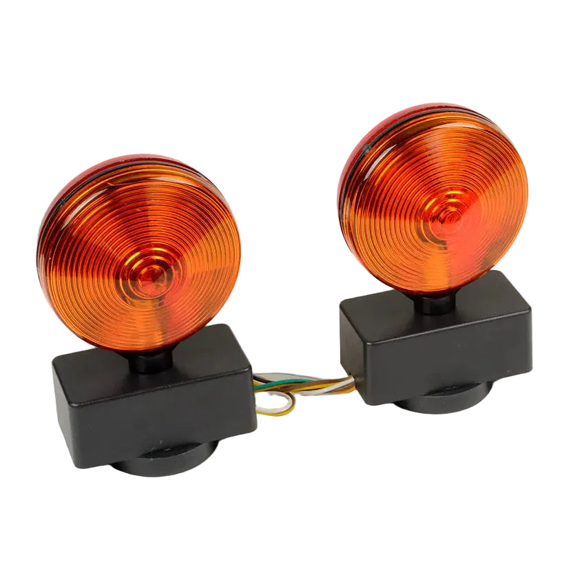A pair of circular amber/orange signal lights with black rectangular bases and visible wiring, photographed on a plain light background.